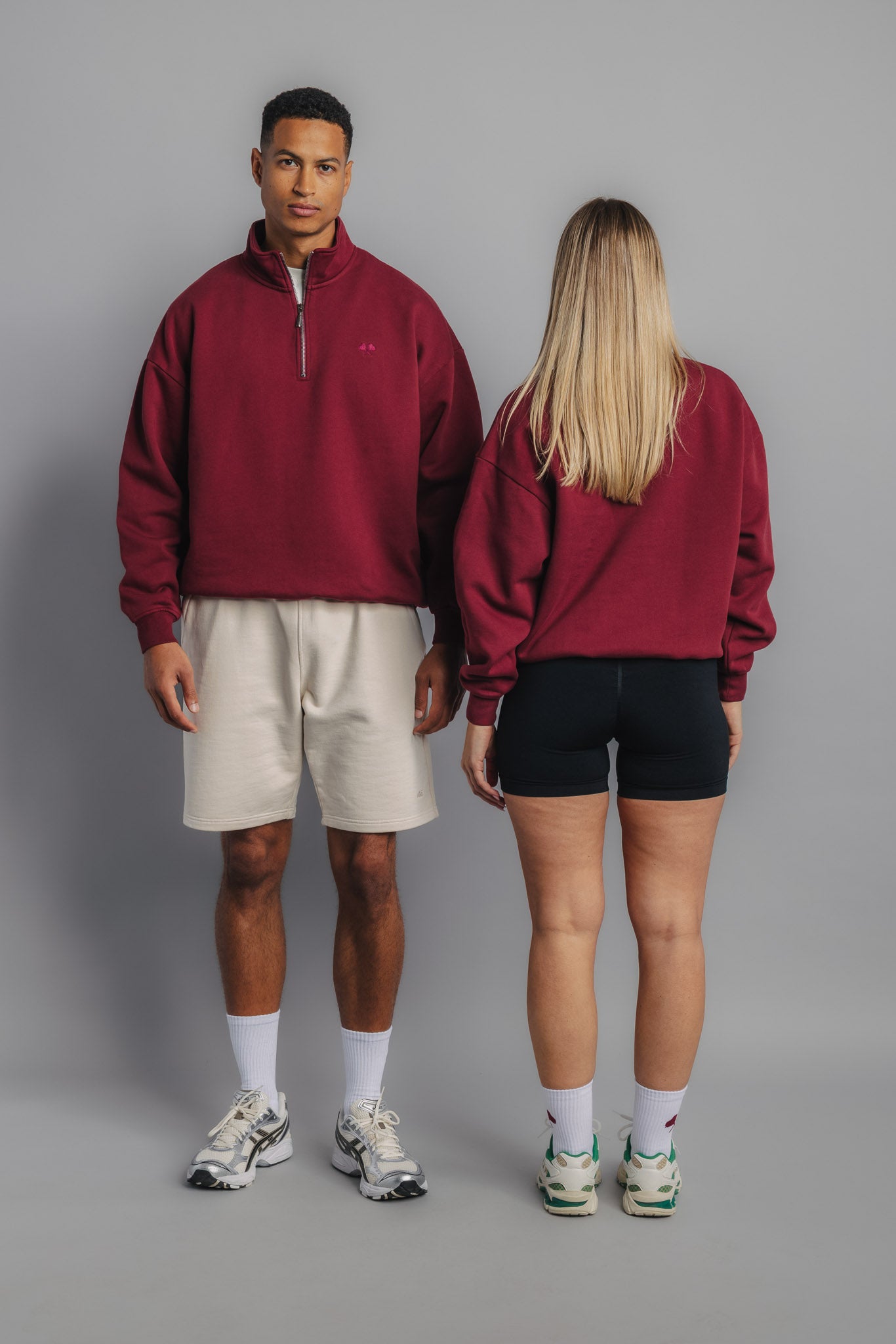 Tennis models wearing burgundy sweaters, one showing front with chest embroidery, the other showing plain back view.