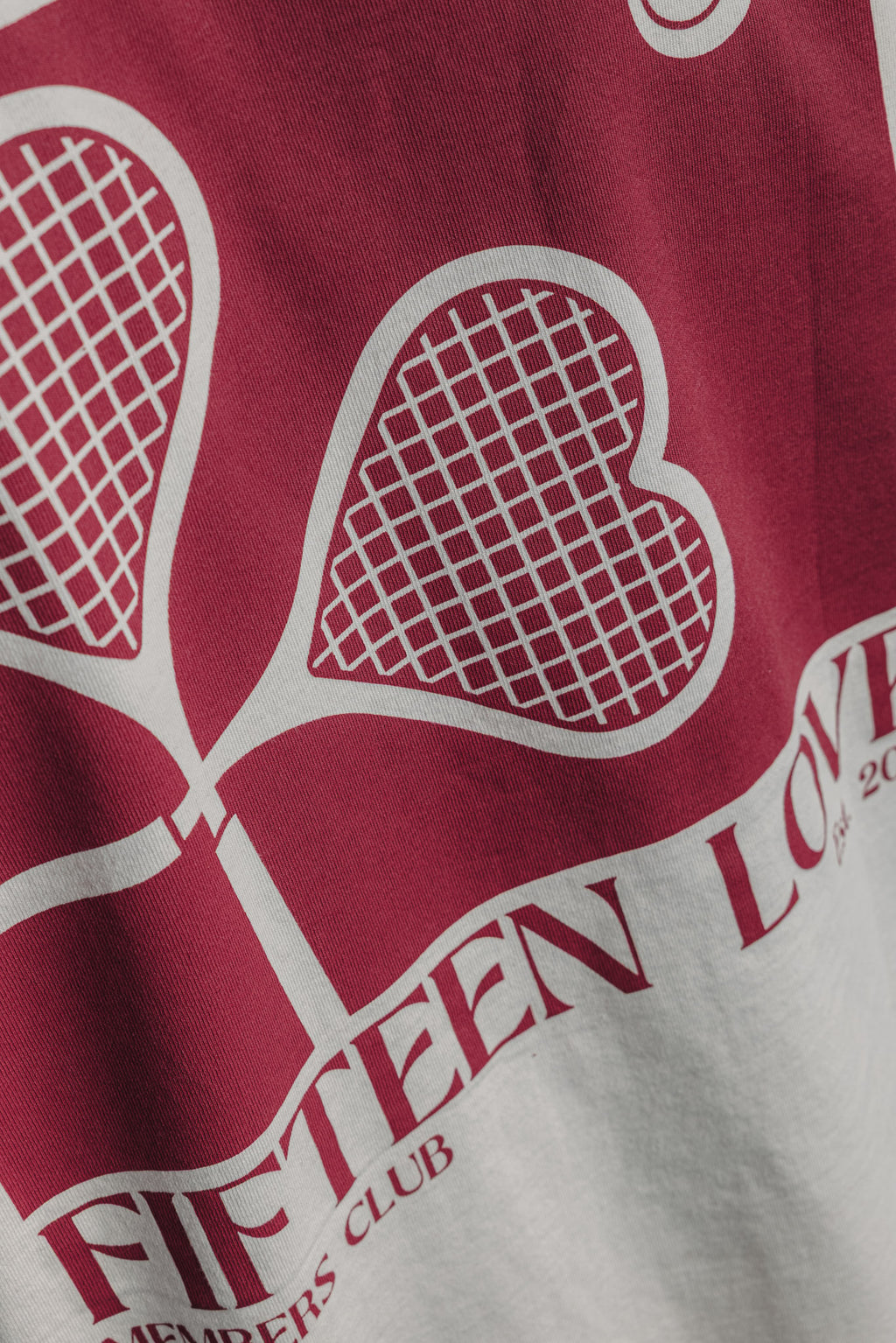Close-up of large heart racquet backprint on white tennis tee, detailed tennis-inspired design.