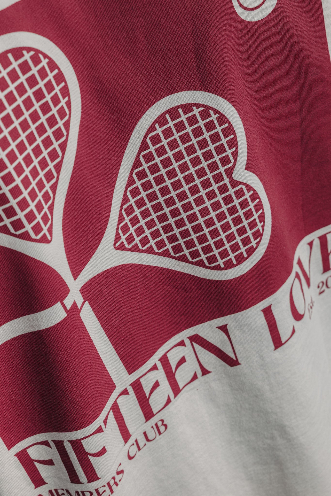 Close-up of large heart racquet backprint on white tennis tee, detailed tennis-inspired design.