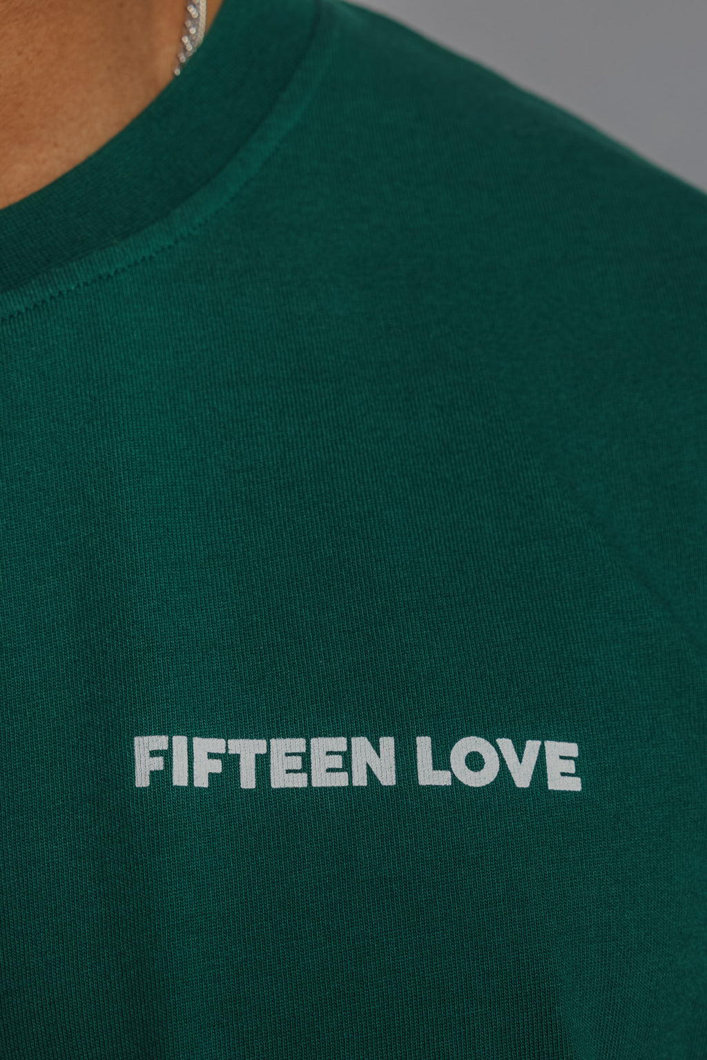 Close-up of small FL logo print on chest of court green tennis tee.