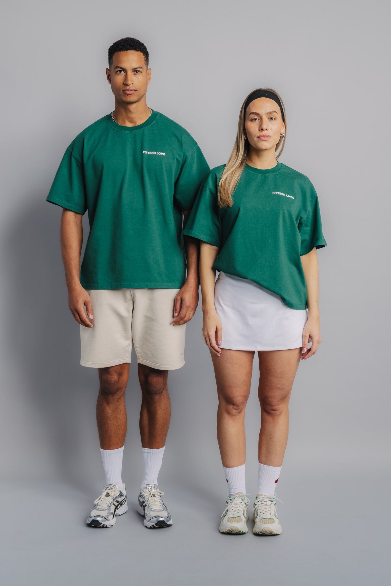 Male and female tennis models wearing court green tee, front view with small embroidered FL logo on chest.