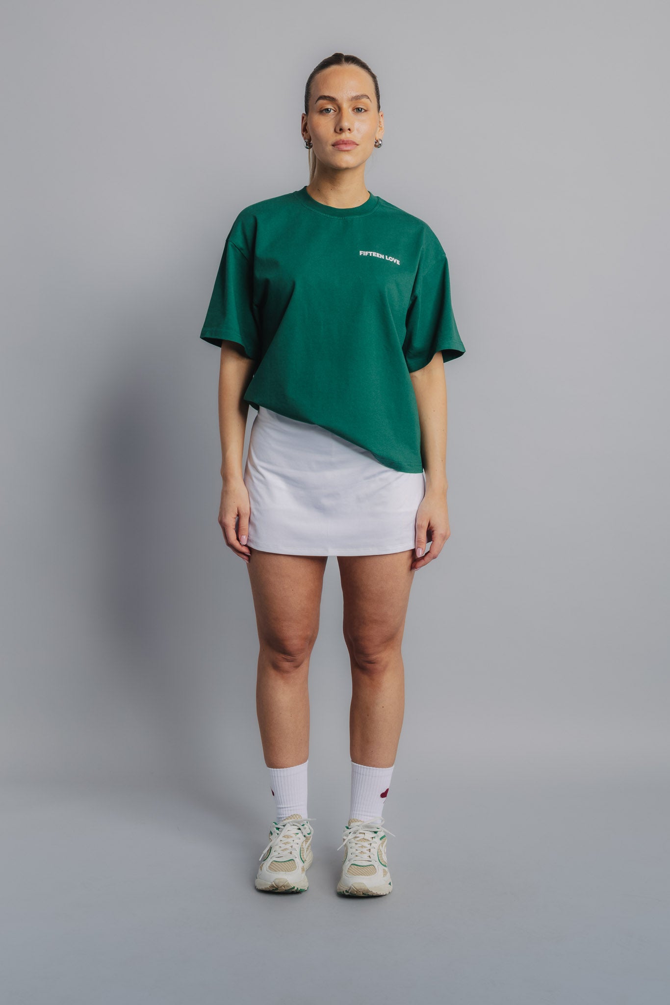 Female model wearing court green tee, front view featuring minimalist FL chest embroidery.