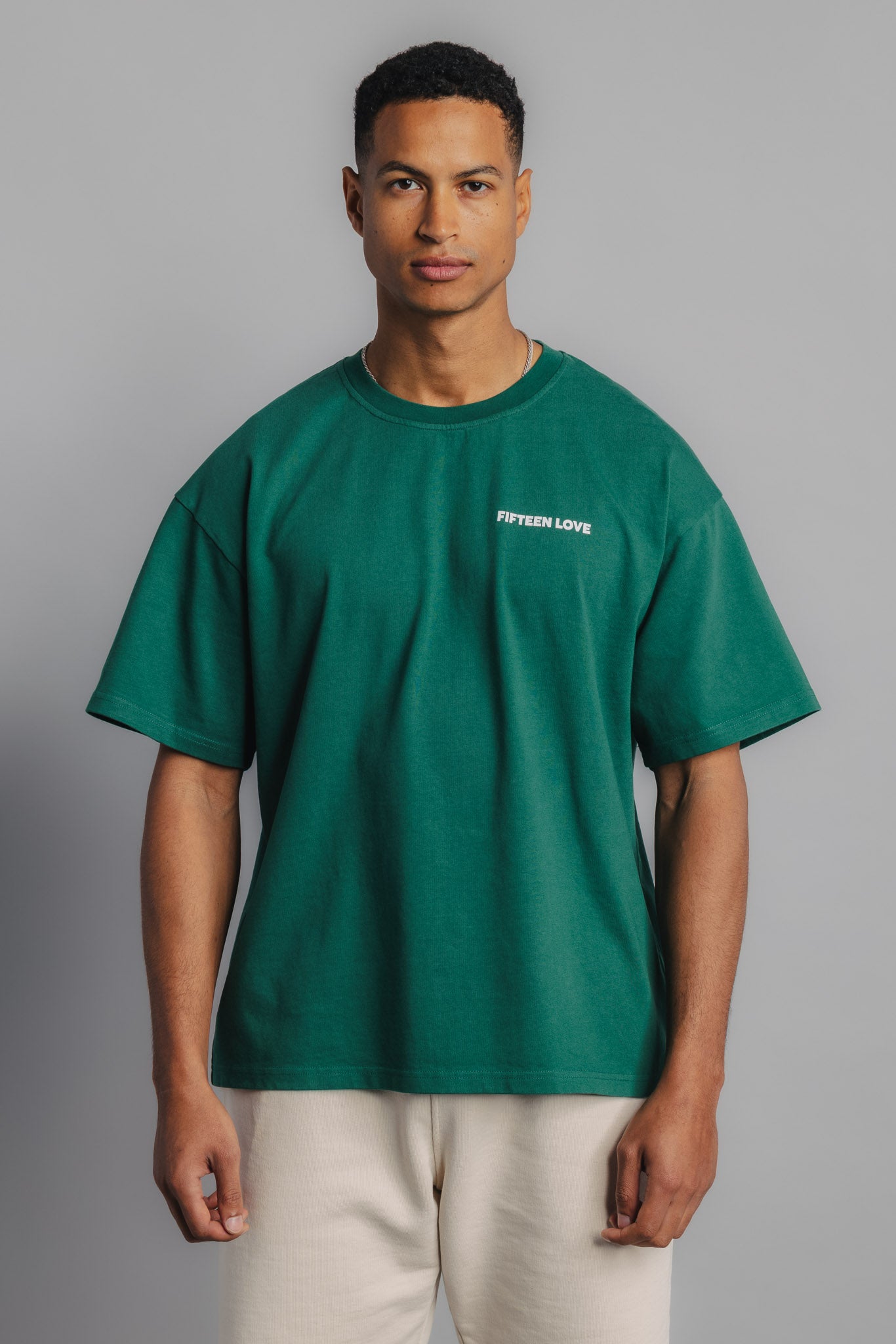 Male model in court green tee with small FL logo embroidery on chest and structured tennis fit.