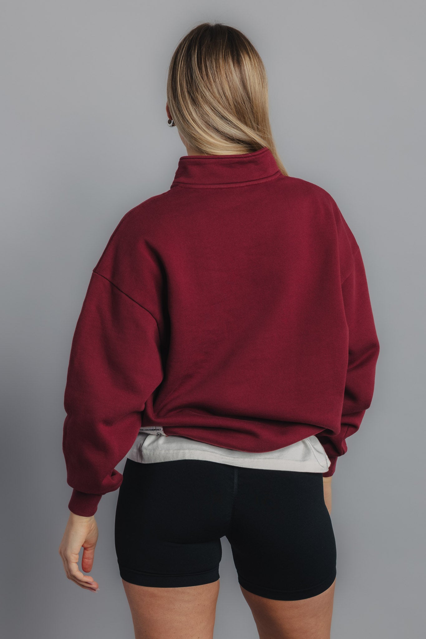 Female model showing plain back of burgundy sweater with clean design and relaxed silhouette.