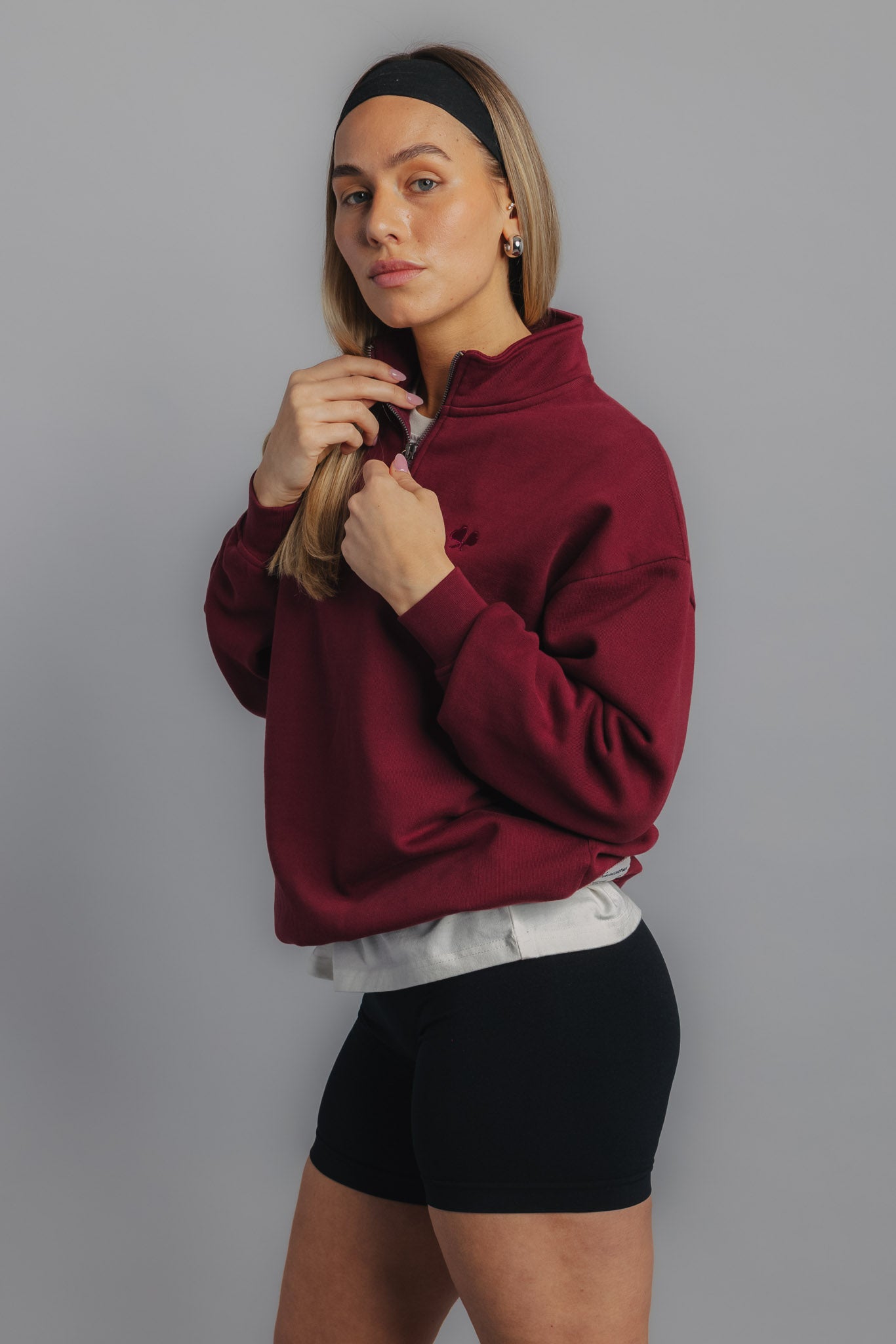 Female model in burgundy tennis sweater, front view with subtle FL chest embroidery and sporty fit.