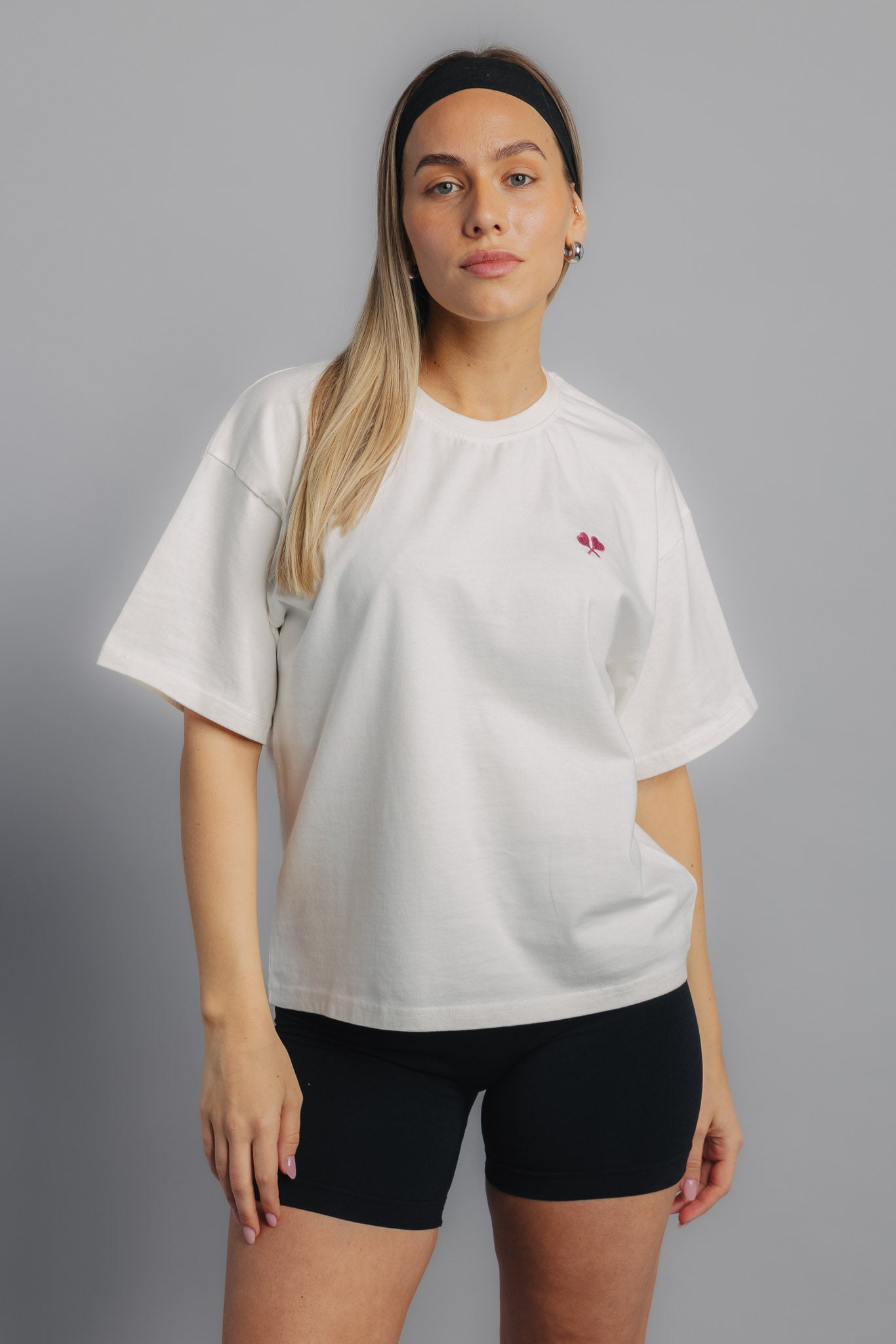Female tennis model wearing white tennis tee, front view highlighting sporty fit and embroidered logo.