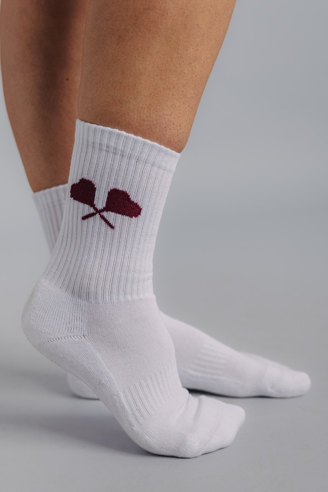 Side view of female tennis sock with heart racquet logo on the side, designed for performance and comfort.