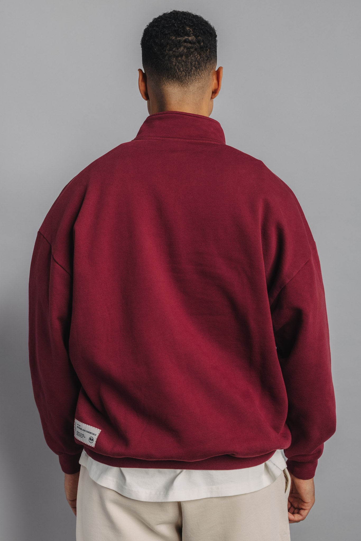 Back view of male model in burgundy sweater with clean, minimal back