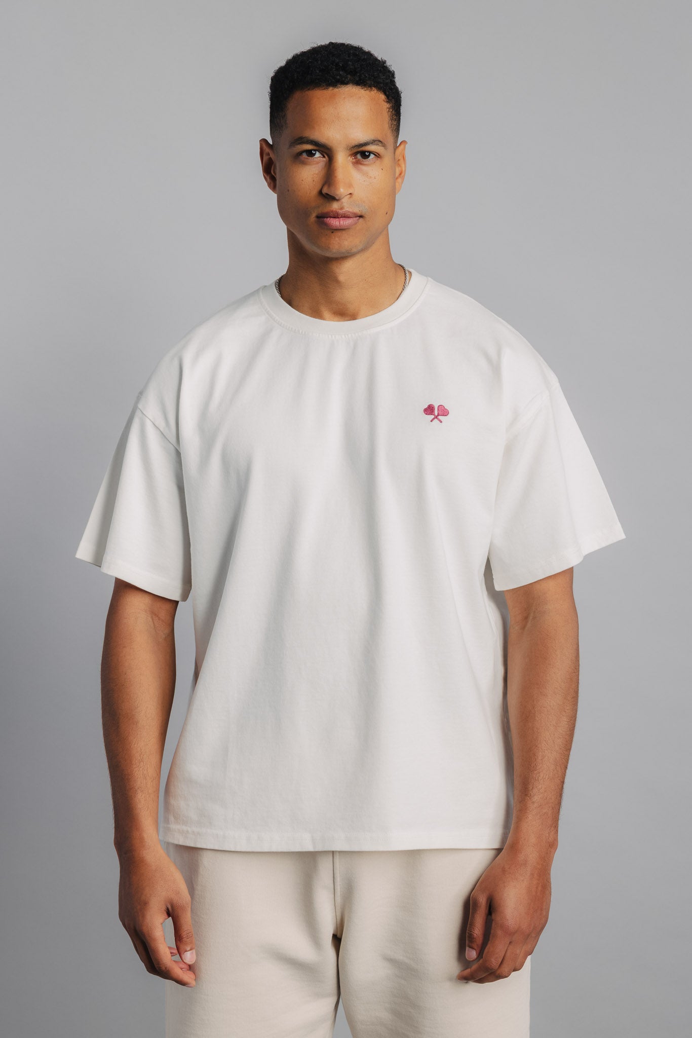 Male tennis model wearing white tennis tee, front view with minimal embroidered logo.