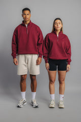 Two tennis models wearing burgundy premium sweaters, front view highlighting high collar and chest embroidery.