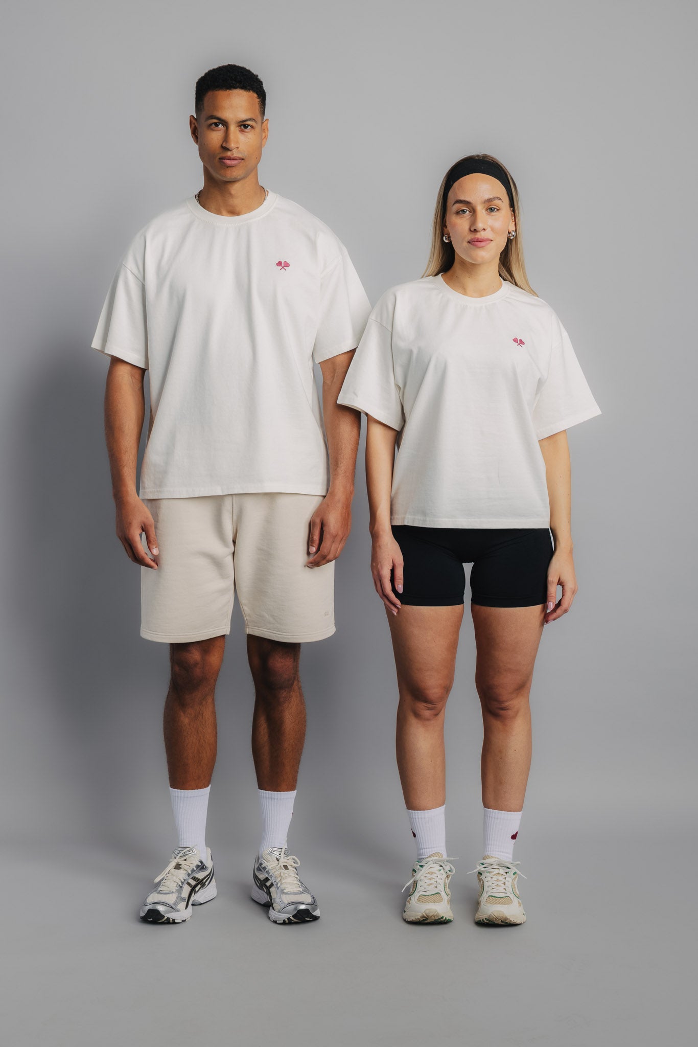 Two tennis models standing side by side wearing white tennis tees, front view showcasing clean design.
